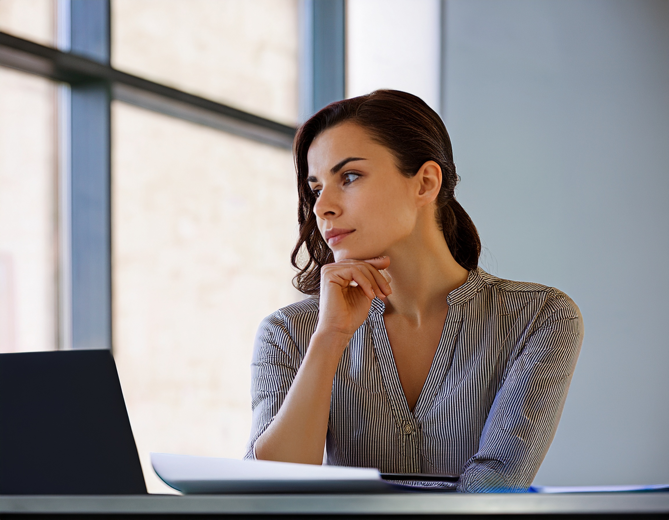 Portrait einer Frau mit einem offenen und zugänglichen Ausdruck, in einem zeitgemäßen Arbeitsumfeld